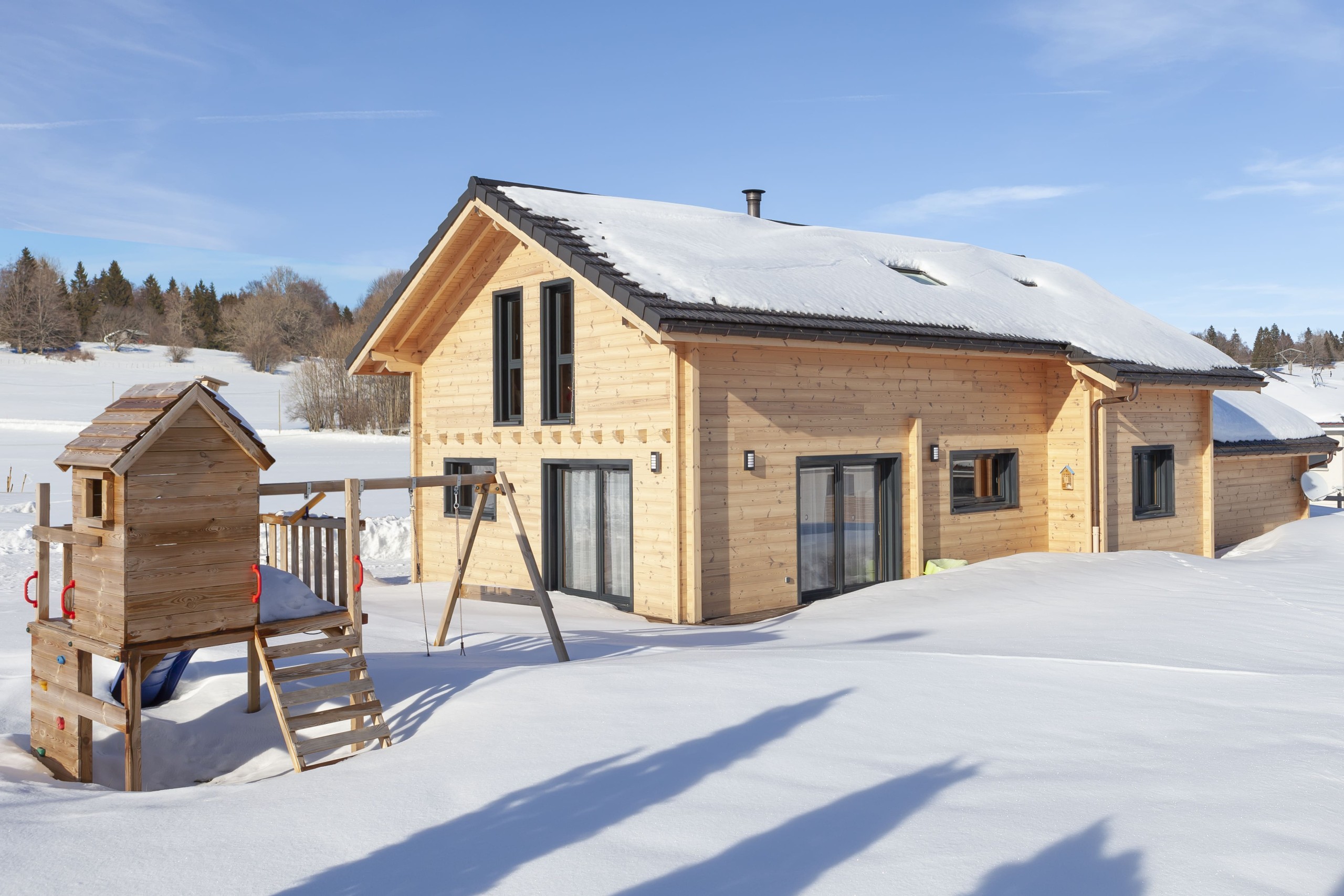 Alliance entre pierres et madrier dans un paysage enneigé.