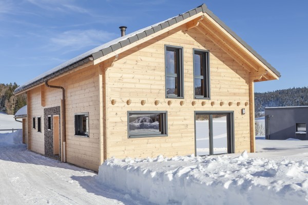 Alliance entre pierres et madrier dans un paysage enneigé (Les Etraches)